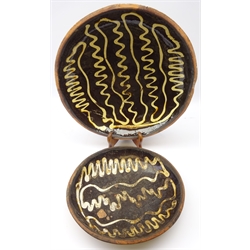  18th century Staffordshire Slipware circular dish, the dark brown ground trailed with wavy formed lines of cream coloured slip and another smaller example, D43cm and D32cm (2)  