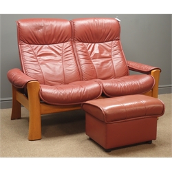  Stressless two seat reclining sofa, (W144cm) and storage stool, with hinged lid upholstered in maroon leather, oak supports  
