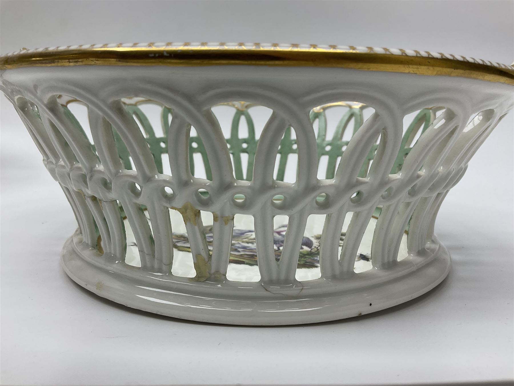Pair of 19th century German openwork chestnut baskets, with twin handles and scrolling gilt border and star rim, painted to the centre with birds and insects, D22cm 