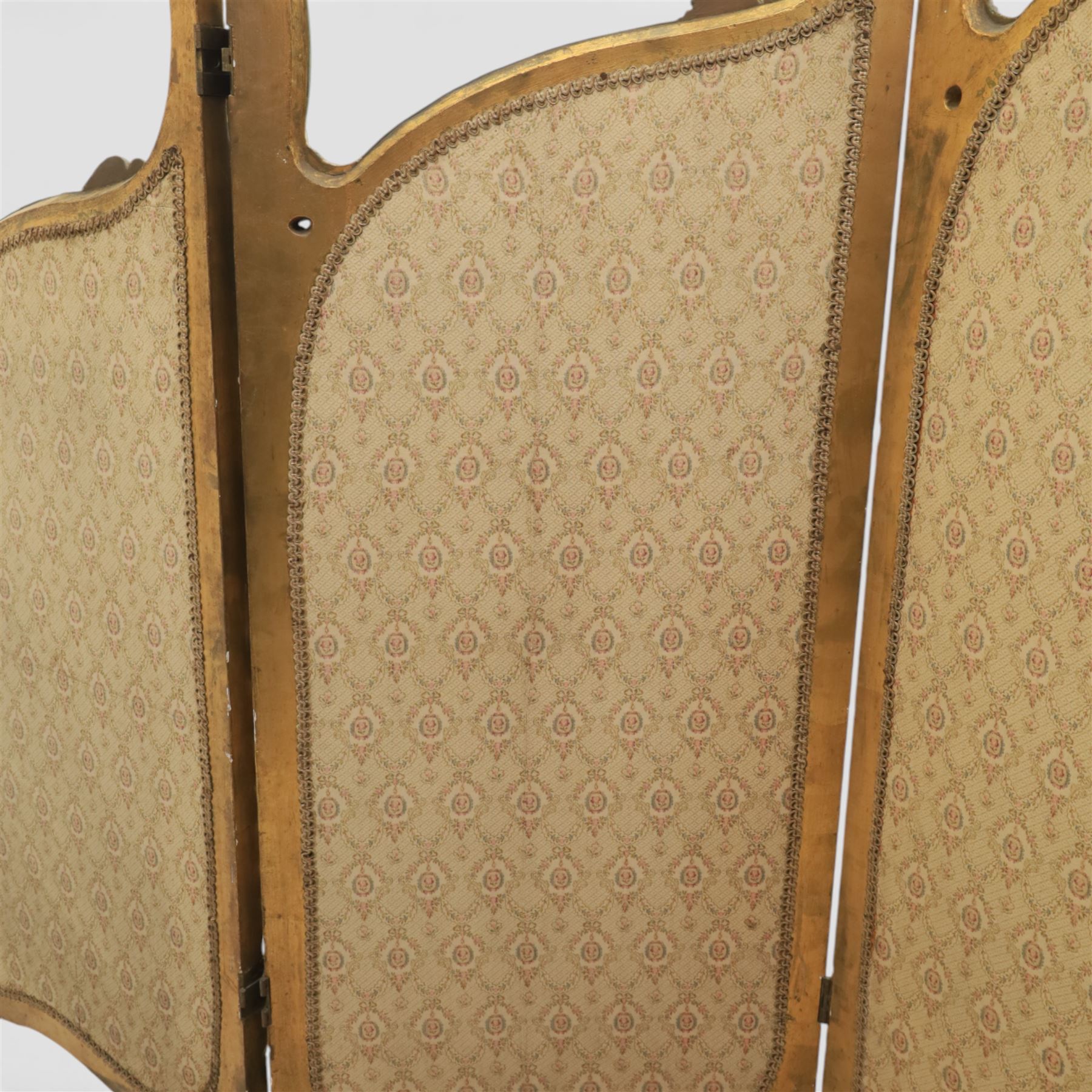 Rococo style giltwood three-panel dressing screen, each panel with shaped and scroll carved frame decorated with shell and foliate motifs, the upper sections glazed, the lower sections upholstered in patterned fabric, hinged to form a folding screen