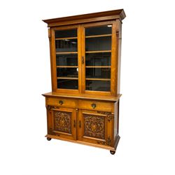 Late 19th century oak bookcase on cupboard, the projecting cornice over two glazed doors and fluted uprights, the cupboard with rectangular moulded top over two drawers and panelled cupboards, the panels carved with scrolling foliage and central cartouche, on turned feet
