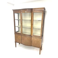 Early 20th century mahogany, inlaid and cross banded break bowfront display cabinet, projecting cornice over two glazed doors and central curved glass panel, lined interior, cupboards below, square tapering supports