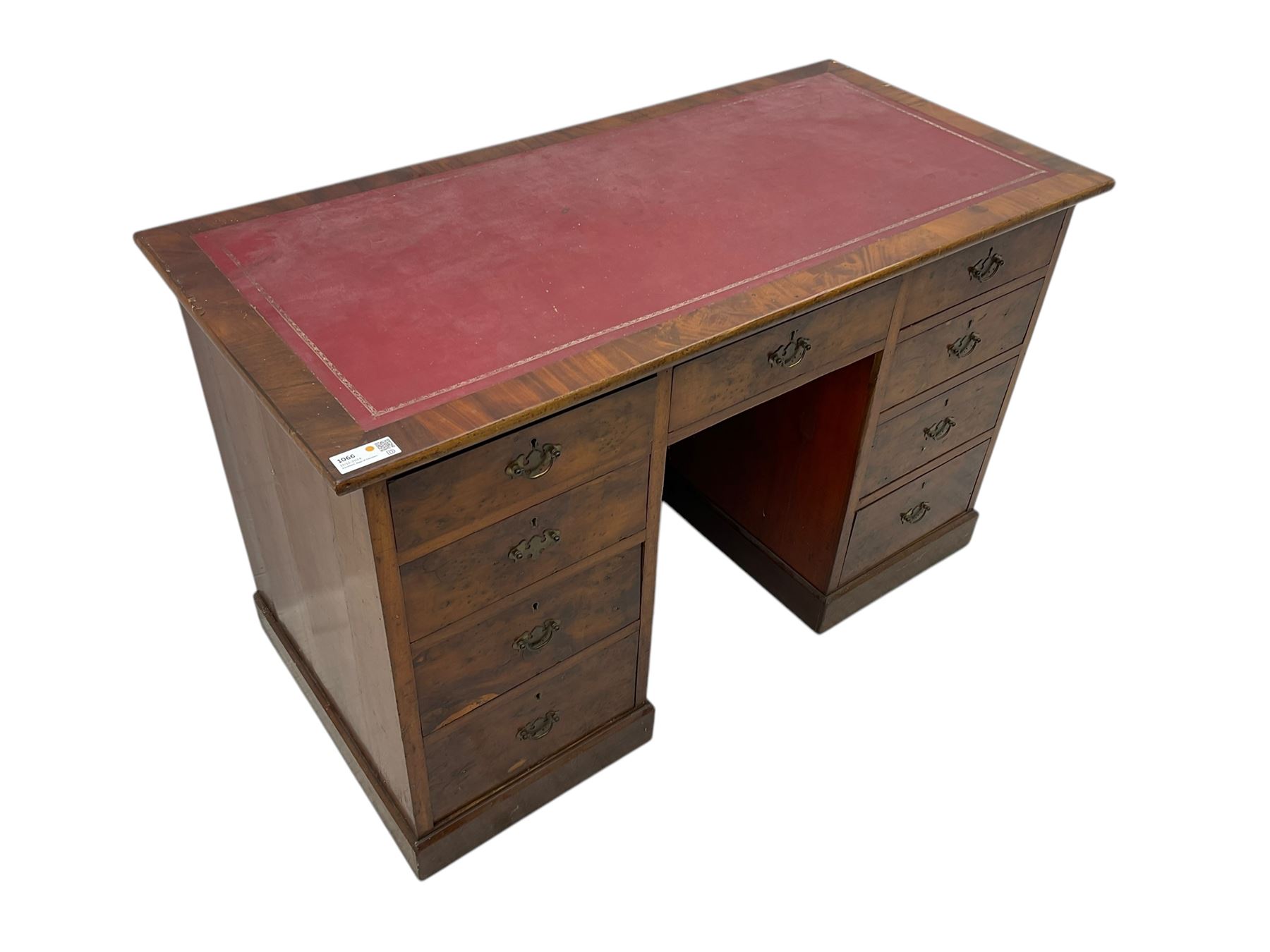 Late 19th to early 20th century walnut pedestal desk, rectangular top inset with red tooled leather writing surface, over a central frieze drawer flanked by two pedestals, each fitted with four graduated drawers with brass escutcheons and drop handles, the whole raised on a plinth base