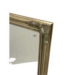 Bevelled mirror in swept silvered frame decorated with foliate cartouches