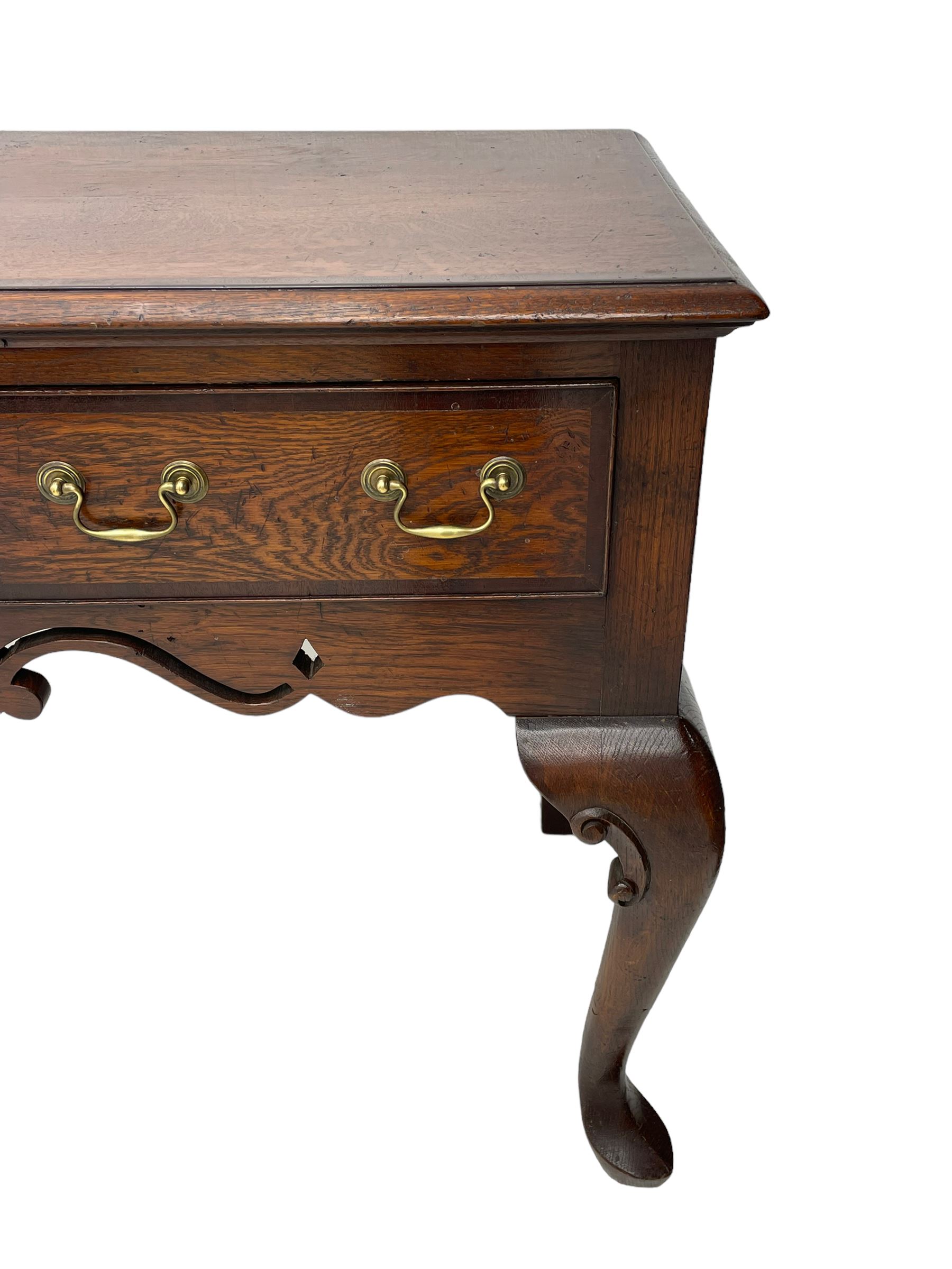 Georgian design oak and mahogany dresser base, the rectangular moulded top with mahogany band, three cocked-beaded and banded drawers over shaped a pierced apron, circular brass handle plates and swan neck handles, on C-scroll carved cabriole supports 