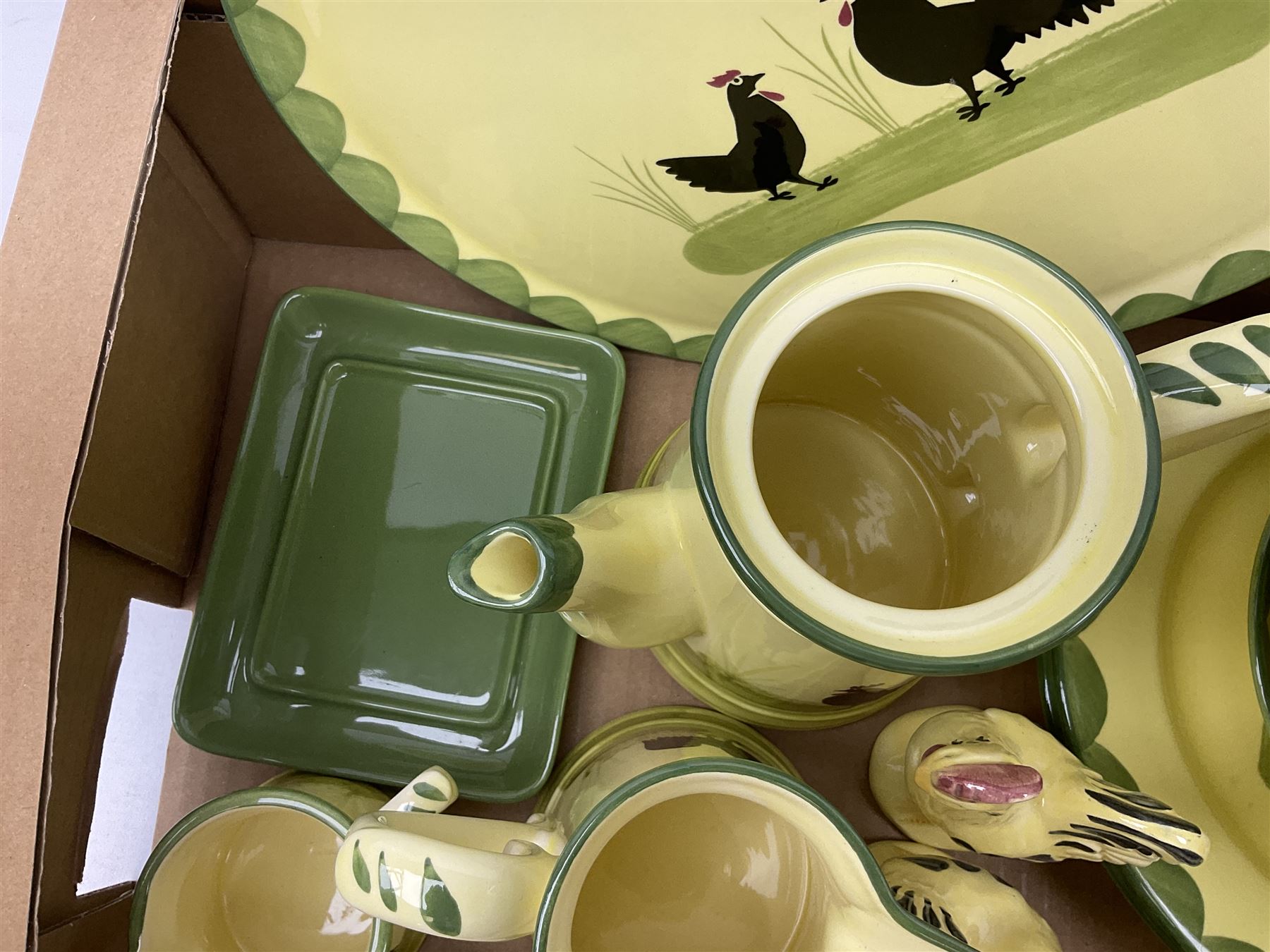 Zeller Fayencerie dinner and tea wares, decorated in cockerels against a yellow ground, with green scalloped border, comprising cake stand, two plates, bowl, three large teacups and saucers, coffee pot, milk jug, cream jug, lidded sugar bowl, pair of cruets modelled as cockerels, butter dish and cover, and utensils pot, and four similar egg cups, in one box 