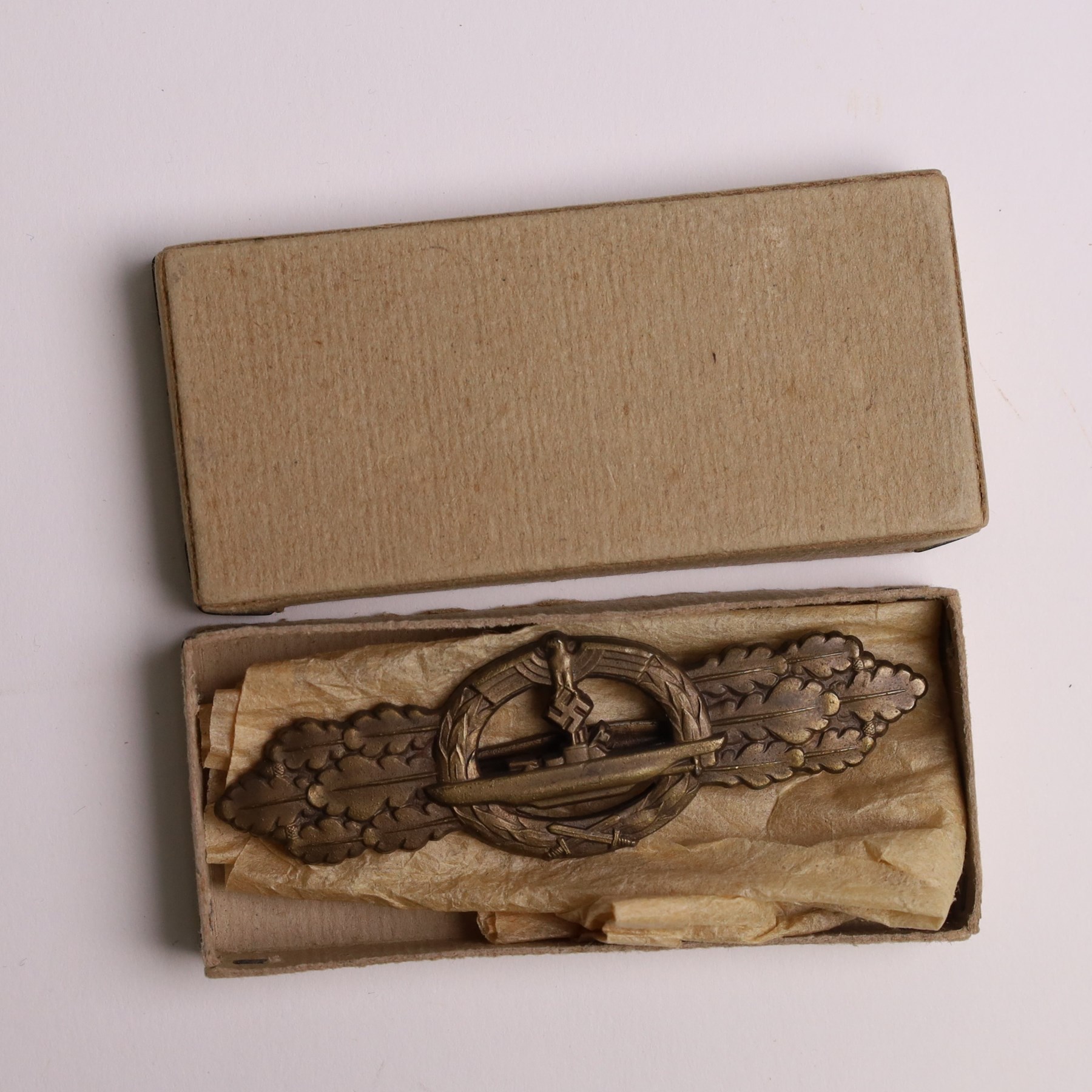 WWII German Kriegsmarine U-Boat combat clasp in bronze by Schwerin Berlin, with the original horizontal pin and catch fixing, makers mark to the reverse “ENTWURF PEEKHAUS AUSF SCHWERIN BERLIN 68” in original packaging