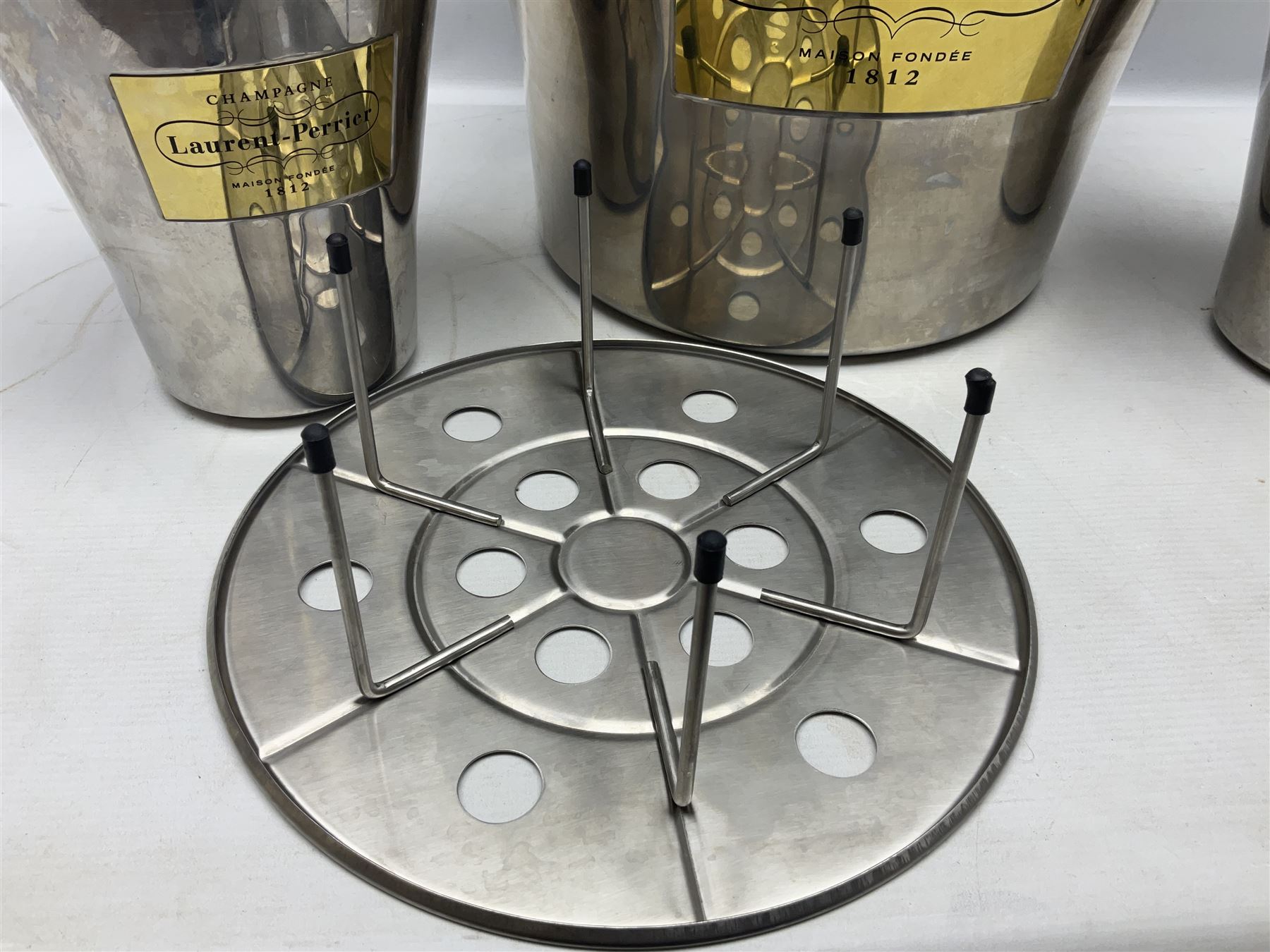 Stainless steel Laurent-Perrier champagne bucket, with engraved brass plaque and grip to swing handle, together with two matching smaller, largest D38cm (3)
