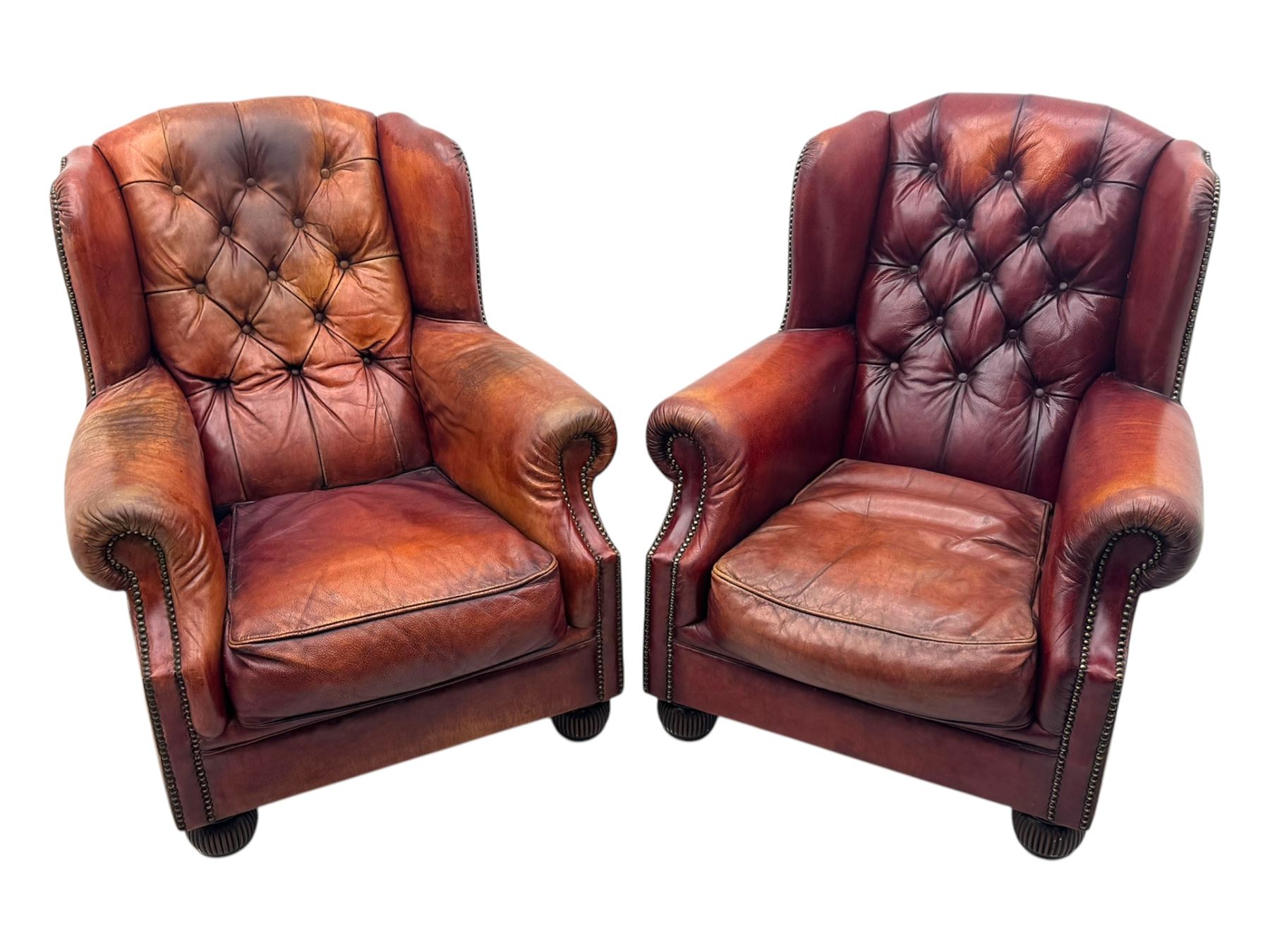 Tetrad - pair of 'Oskar' wingback armchairs, deep-buttoned oxblood leather upholstery with rolled arms and brass stud trim, raised on turned and reed moulded feet