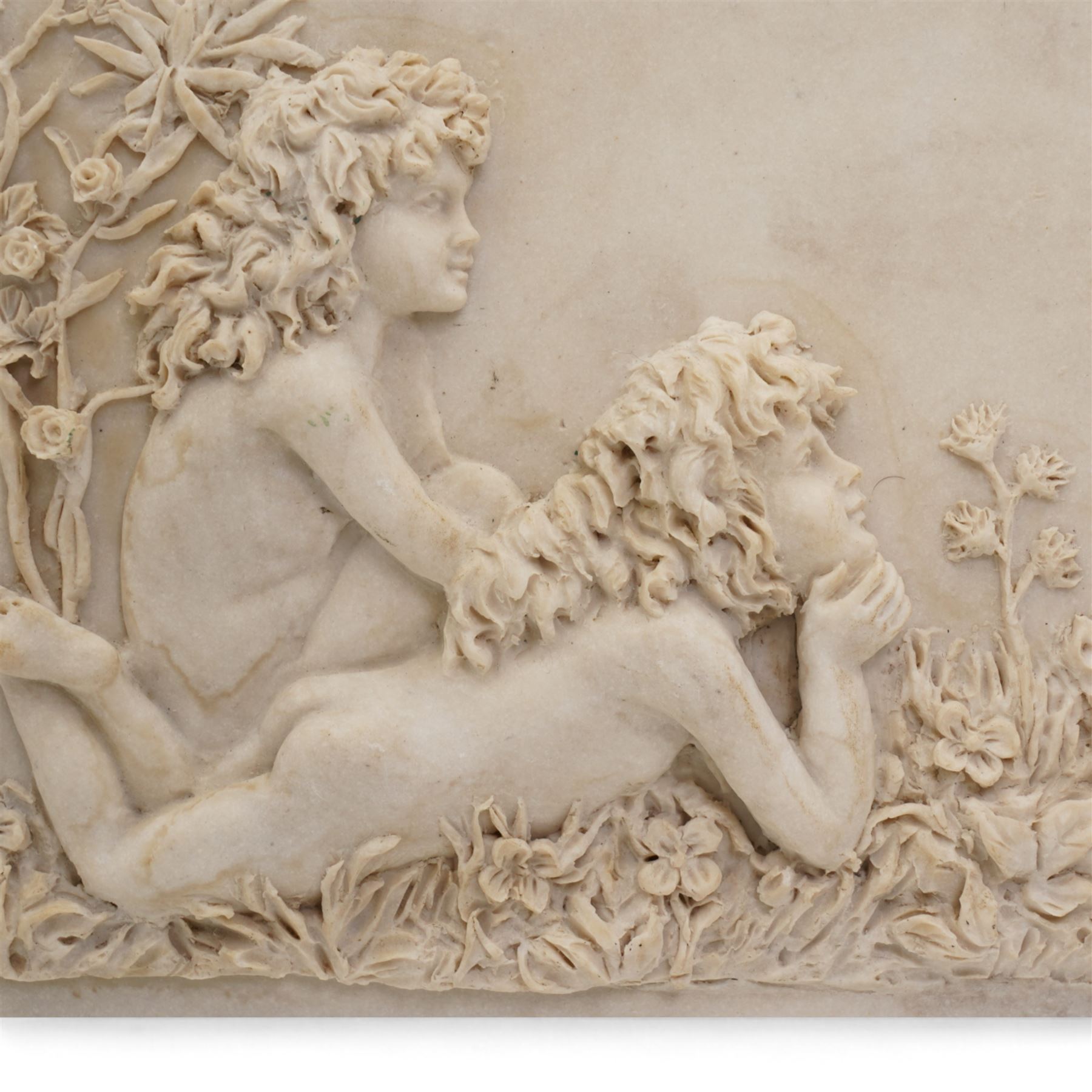 Composite plaque, depicting Sprites in a garden, with inset 'Arts and Commerce Promoted' medallion to reverse, 20cm x 33cm; together with a moulded glass Claret jug with silver plated mount H30cm 