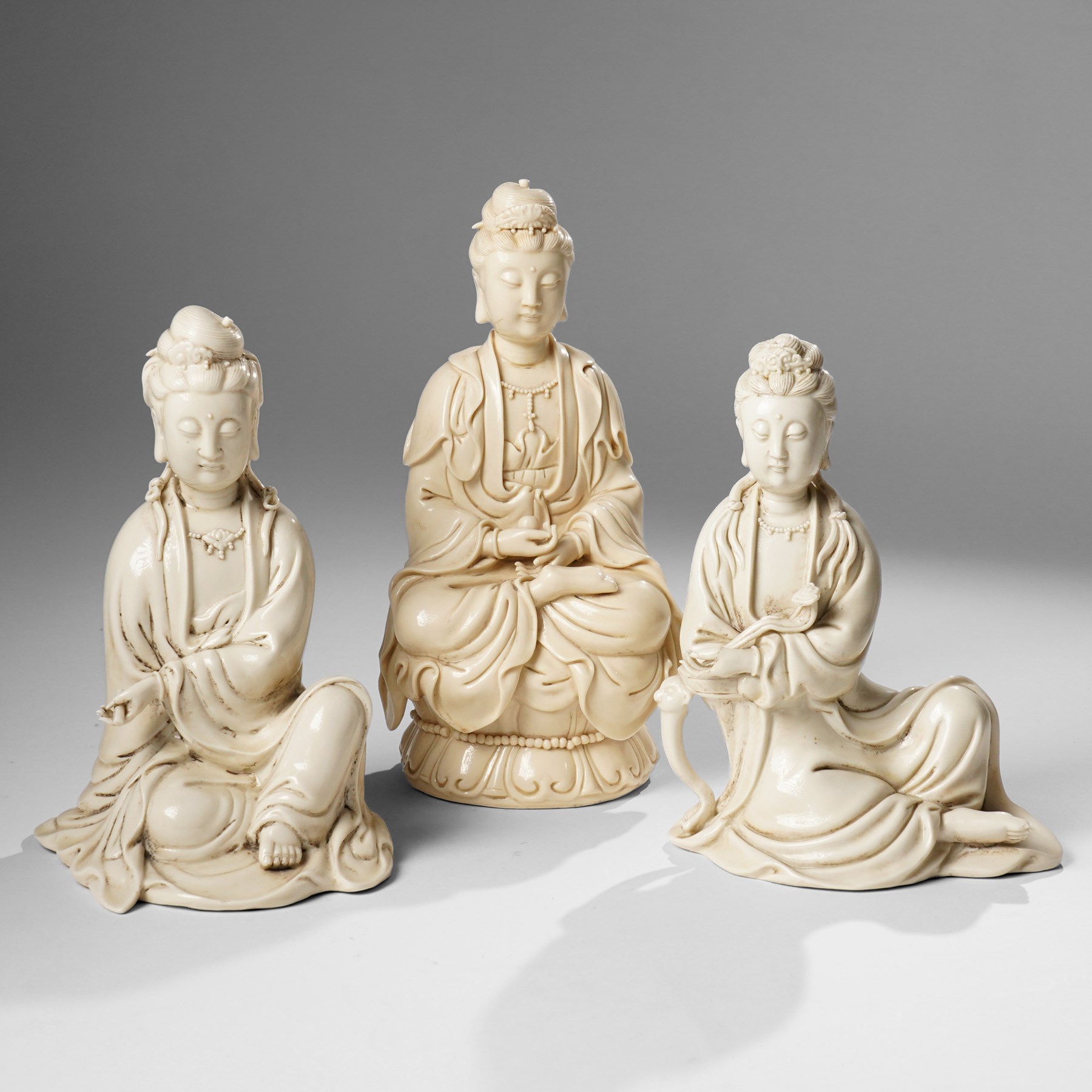 Three Chinese blanc de chine figures, each depicting Guanyin seated, Dehua province, two with double gourd and potters seal marks to the reverse 