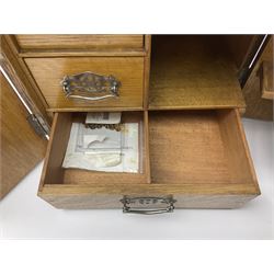 Early 20th century oak smokers cabinet, with brass shield shaped mounts, opening to reveal a compartmentalised interior with three drawers, pipe rack and tobacco jar, together with a small wooden shelf, smokers cabinet H28.5cm