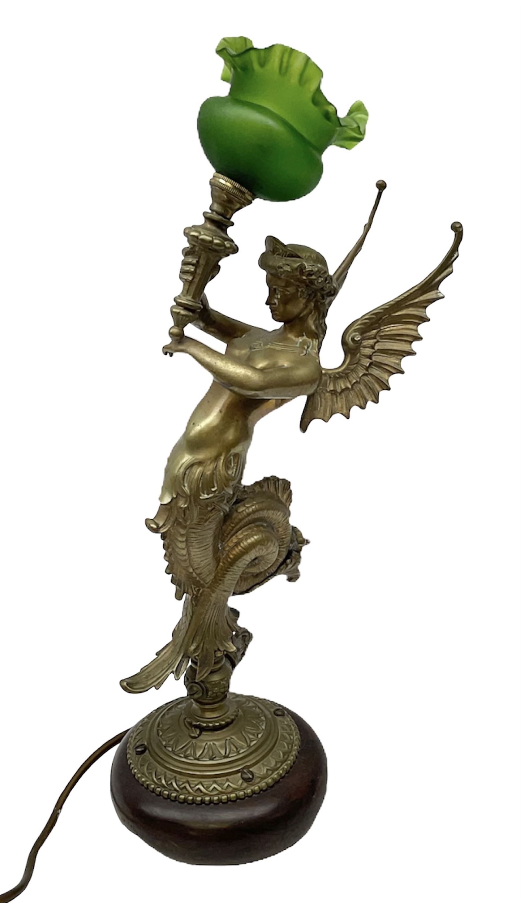Victorian gilt bronze converted gas lamp in the form of  mythical winged mermaid upon a circular oak base, with a frilled green glass shade, H44cm