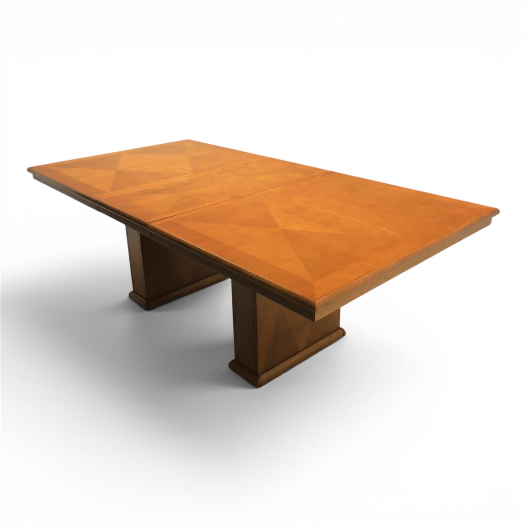 Modern Art Deco design walnut extending dining table, rectangular top with rounded moulded edge, geometric parquetry veneered panels, extending action with additional leaf extending to 220cm, on twin panelled pedestal supports with stepped plinth feet