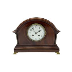 Mahogany cased eight-day mantle clock c1910 with an eight-day spring driven French movement striking the hours and half hours on a coiled gong, case with a break arch top and contrasting inlaid stringing to the front, with recessed brass pillars, plinth raised on bracket feet, enamel dial with Arabic numerals and spade hands, convex glass within a brass bezel. With Pendulum.

