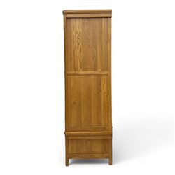 Modern light oak double wardrobe, with twin panelled doors enclosing hanging rail and full-height interior, above a deep lower drawer with recessed handle, shaped stiles