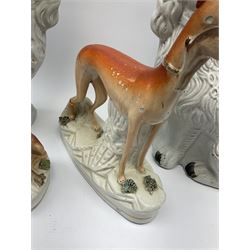 A pair of Victorian Staffordshire white glazed spaniels, together with two Victorian Staffordshire models of greyhounds, the largest modelled with hare in mouth, largest greyhound H27cm. 