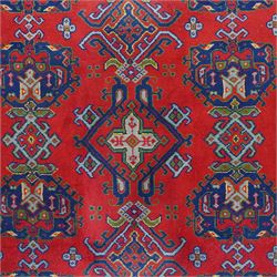 Indian Kayam rug, the rectangular field with repeating geometric medallions on a red ground, within a blue border of stylised floral motifs, with guard borders and fringe terminals
