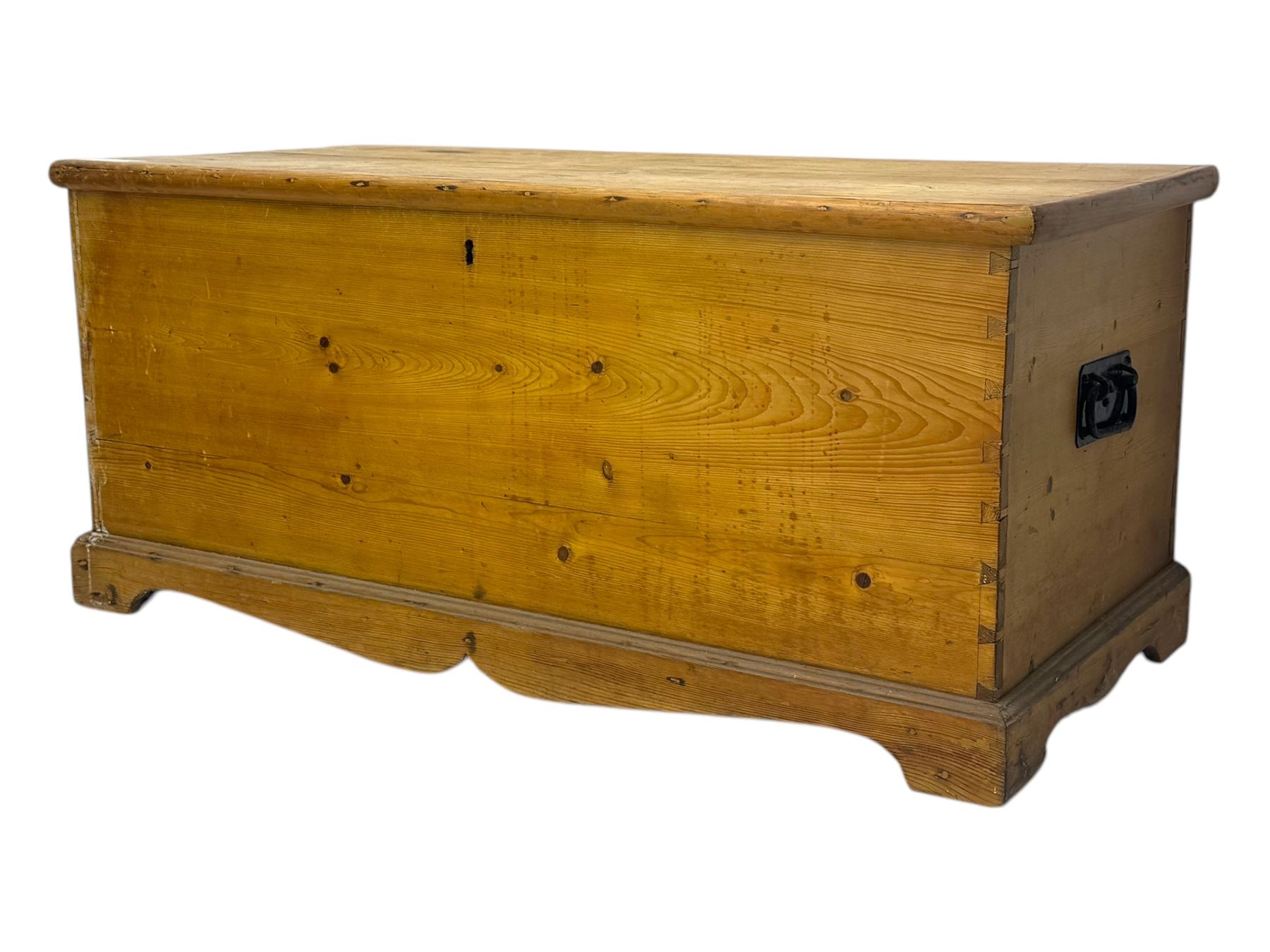 Late 19th century stripped pine blanket box, rectangular hinged lid enclosing main compartment with fitted candle box, wrought iron strap hinges and lock, black-painted side handles, on a shaped plinth base