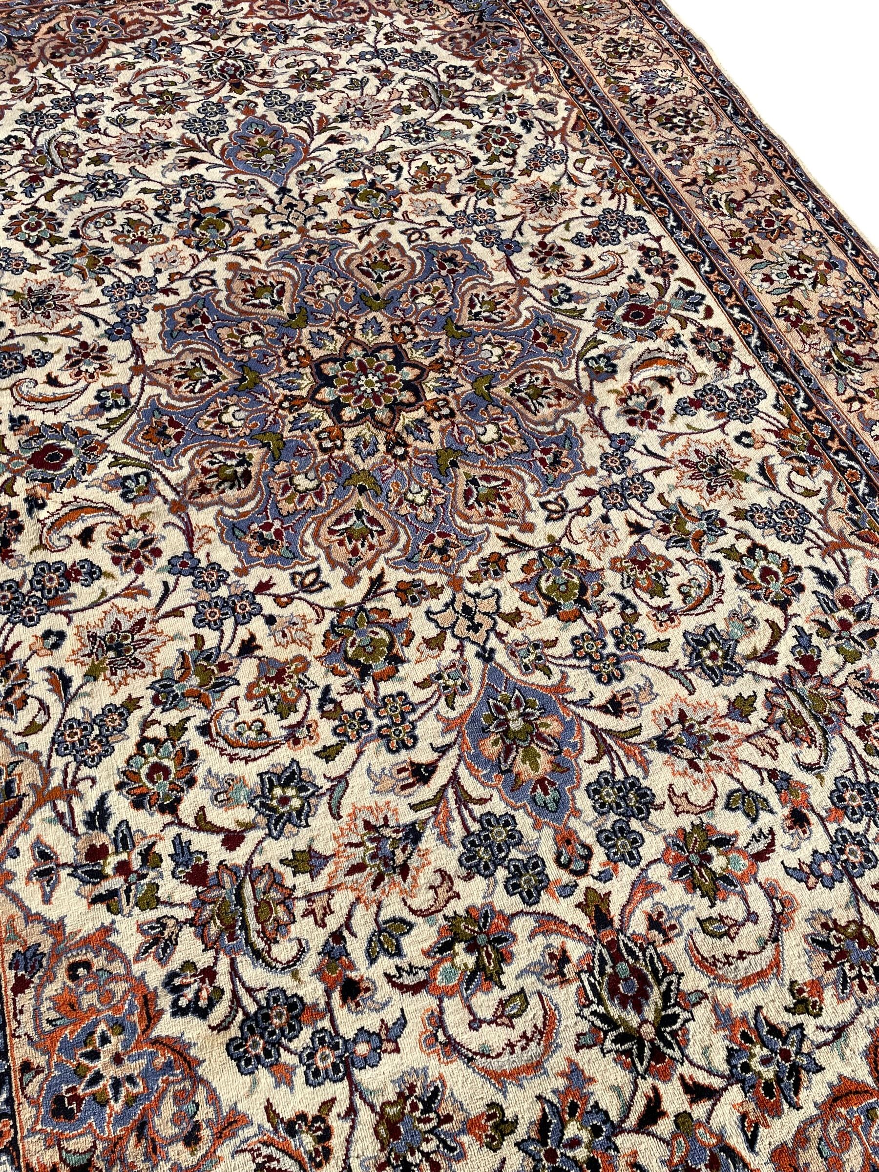 Persian Najafabad ivory and peach ground rug, central rosette medallion surrounded by swirling leafy branches and palmettes, trailing border decorated with stylised plant motifs, enclosed within floral pattern guard stripes