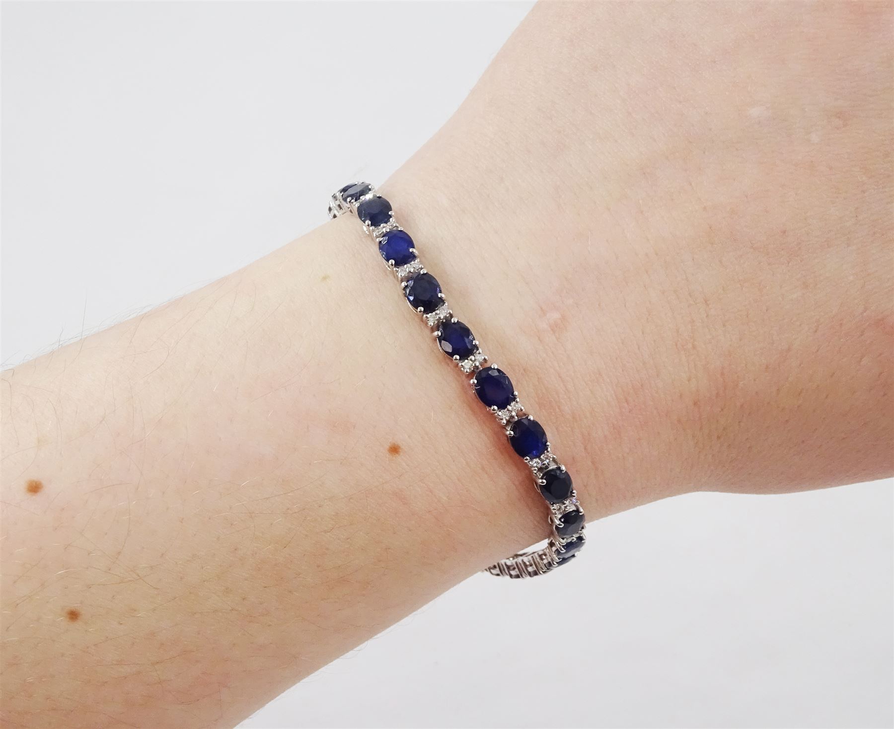 18ct white gold sapphire and diamond bracelet, twenty-six oval cut sapphires, each spaced by two round brilliant cut diamonds, stamped 750, total sapphire weight 10.60 carat, total diamond weight 0.46 carat