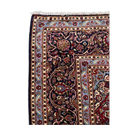 Persian Kashan indigo ground carpet, central floral pattern medallion surrounded by a densely decorated field depicting trailing branches with leaves and palmettes, scrolling border decorated with stylised plant motifs, within floral pattern guard stripes 