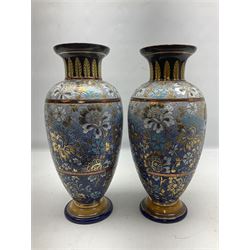 Edwardian pair of Doulton Lambeth stoneware vases, the bodies of baluster form with typical floral and foliate decoration upon merging blue and white ground with copper banding, and flared foliate neck decorated with acanthus leaf detail, decorated with gilt throughout, impressed marks c 1902-1922, and painted marks X 3904, H32cm