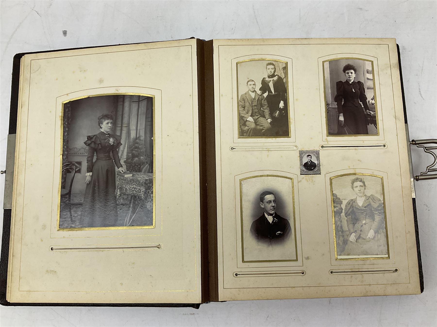 Victorian leather bound photo album, the interior leaves containing apertures of various sizes and shapes of portraits surrounded by printed floral designs, H28cm