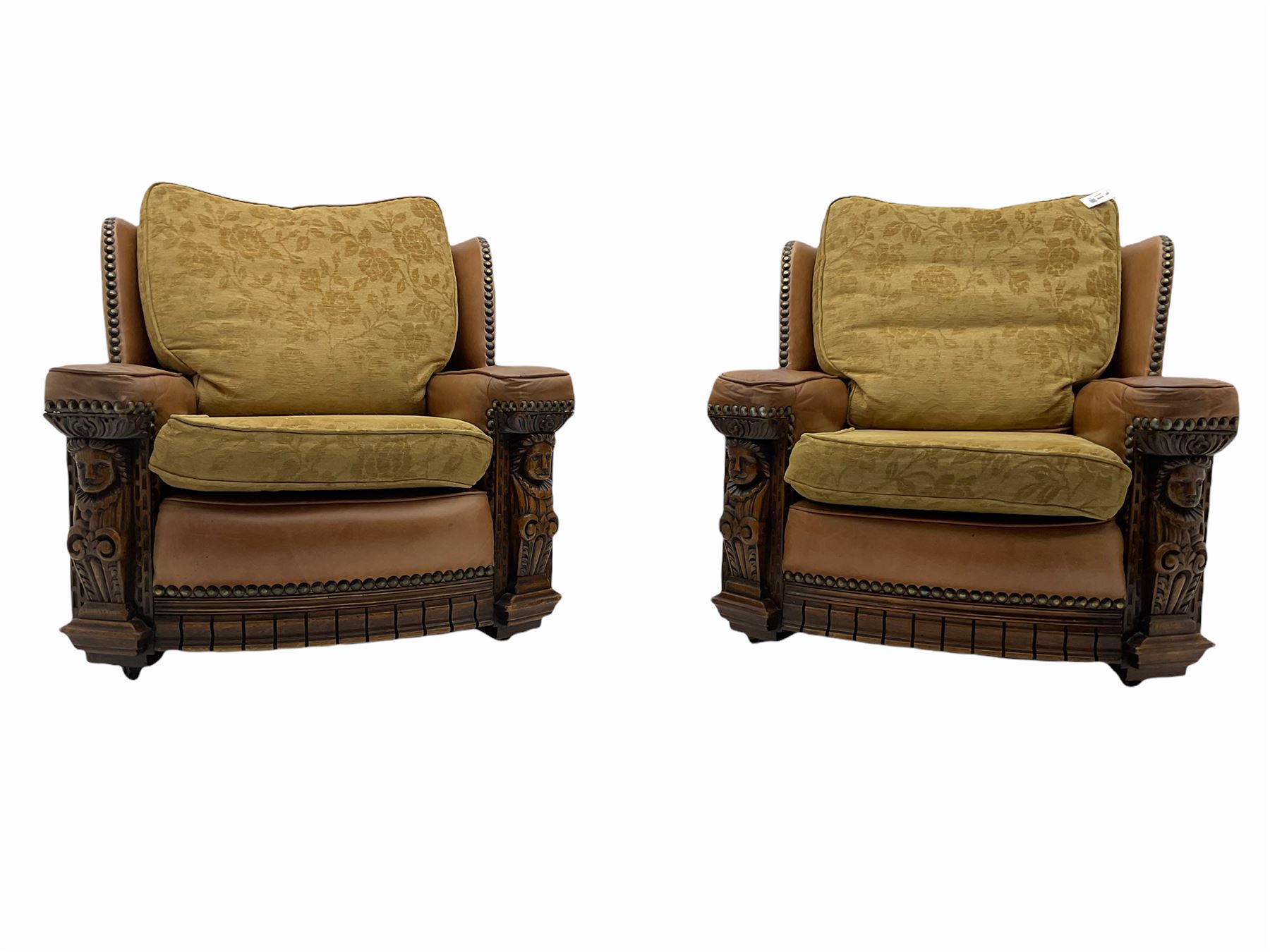 Pair of 1930’s carved oak framed club chairs, upholstered in tan studded leather with beige fabric loose cushions