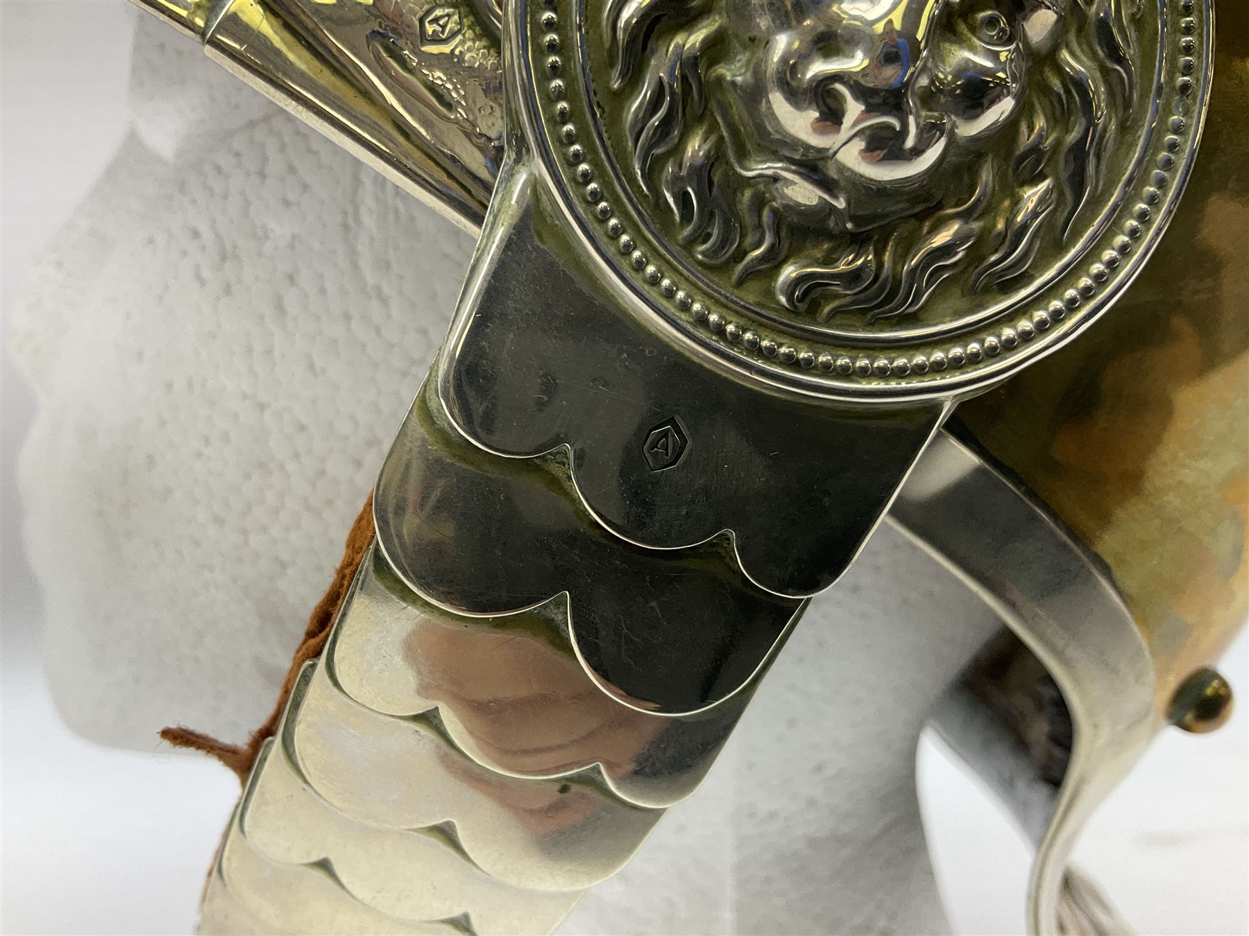 Early 20th century French mounted gendarme's helmet, brass with nickel-silver mountings, broad band embossed with fused grenade, high comb with the face of the gorgon Medusa at the peak and with a black horse hair crest, plume socket at the left, leather-backed nickel-silver chin scales with lion mask mounts.