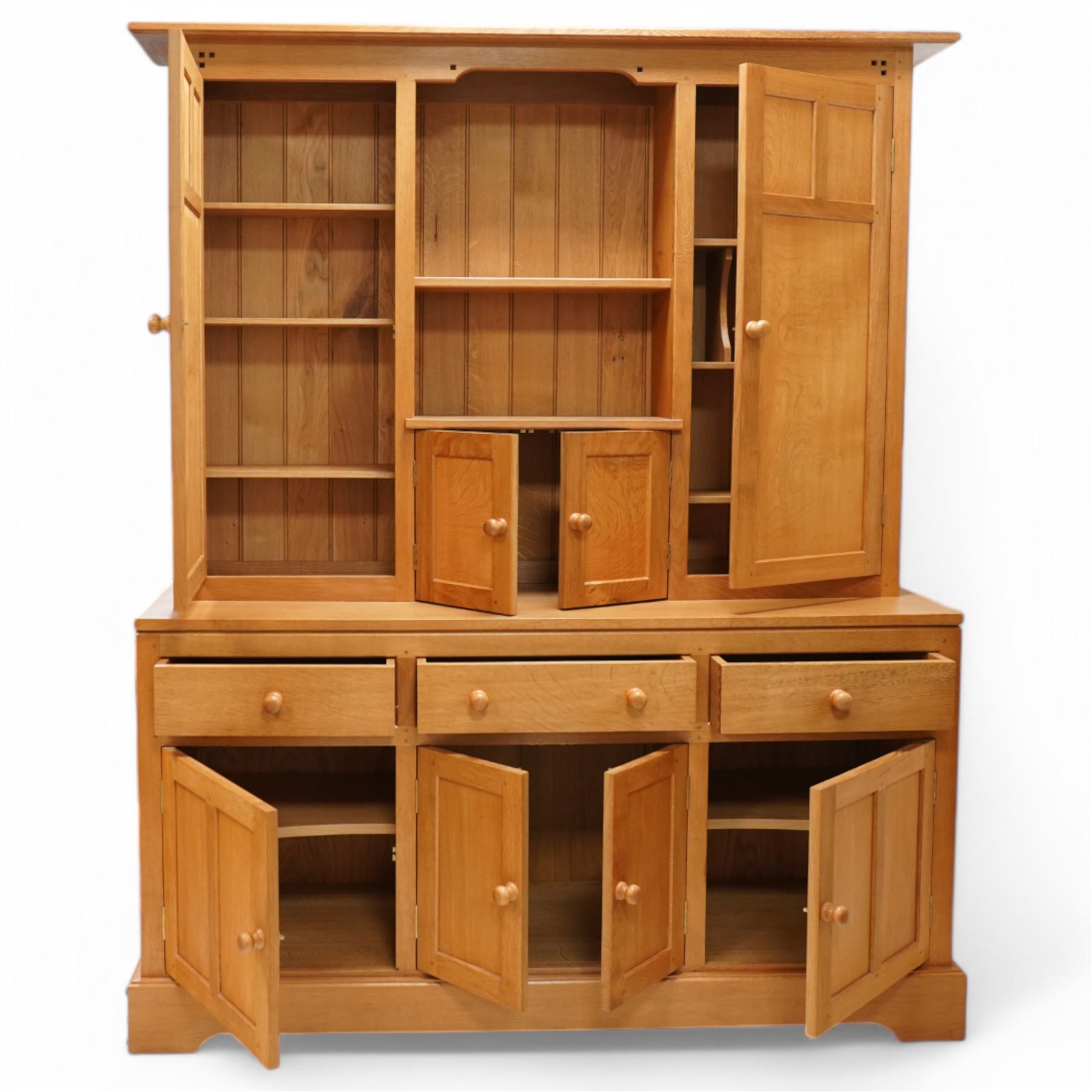 Yorkshire oak dresser, projecting top over open centre fitted with shelf, small double cupboard and flanking full height cupboards, the lower section fitted with three drawers and cupboards, enclosed by panelled doors, on plinth base
