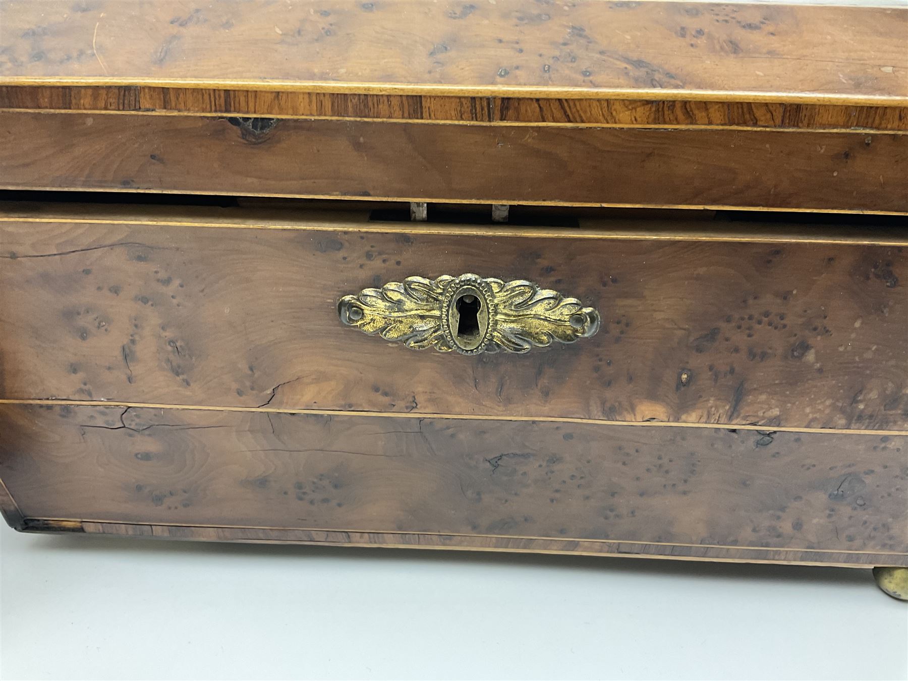19th century burr yew wood tea caddy, of sarcophagus form, with strung details and brass mounts, the interior split into three compartments, upon four brass bun feet, together with an oak and brass bound writing slope, with red leather interior with gilt detailing, largest H16cm, W40cm