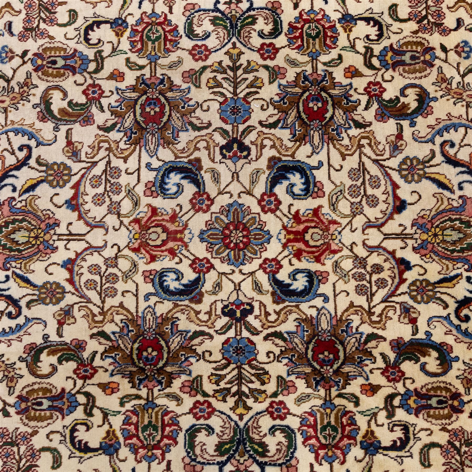North West Persian Tabriz, hand-knotted carpet, ivory ground with dense scrolling vine-work, palmettes, flowering sprays, and stylized leaves framed by a principal border of scrolling floral motifs and palmettes and flanked by narrow guard borders, with cotton fringe ends