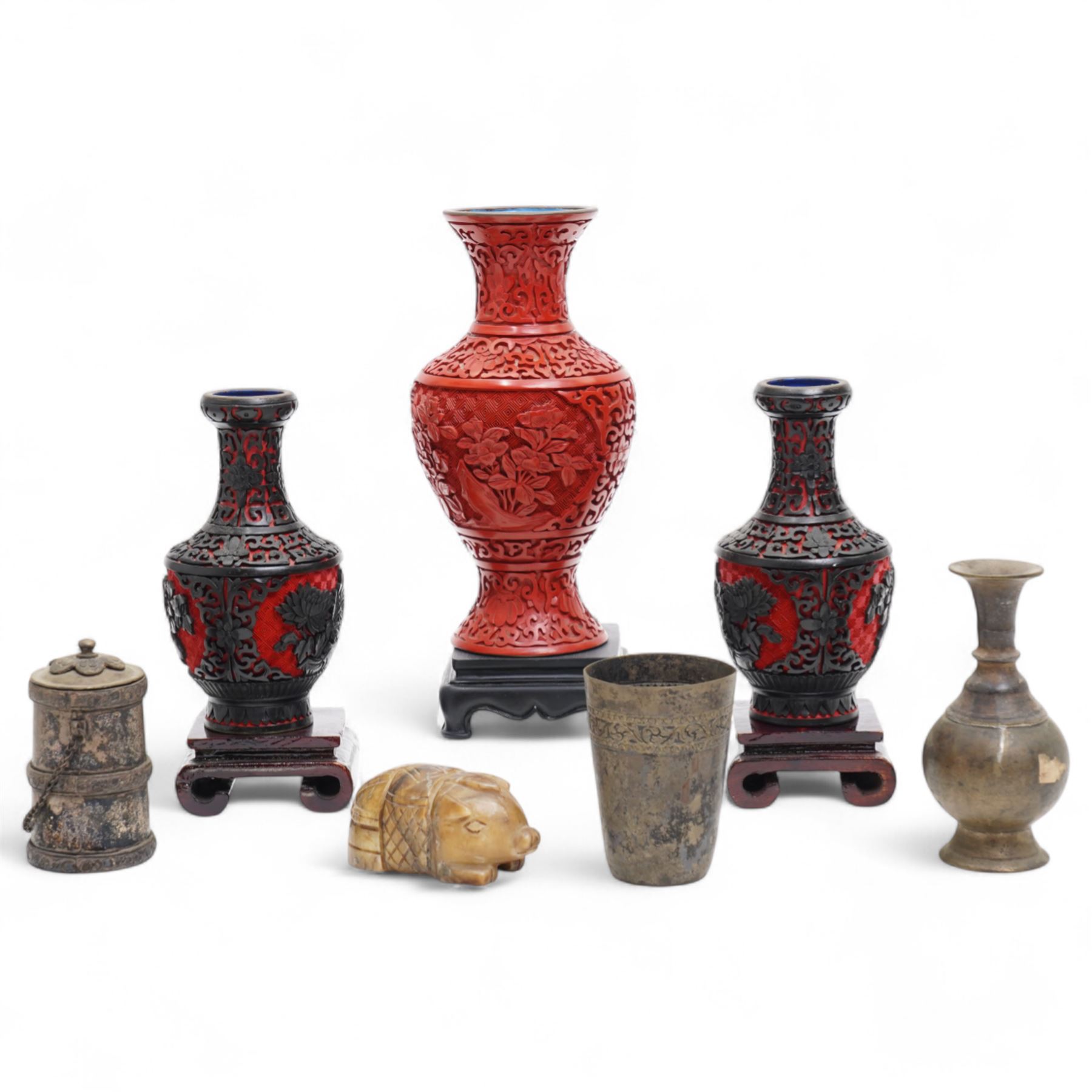 Three Chinese red and black cinnabar lacquered vases, together with three metalware examples, possibly 19th century Islamic, comprising vase, cup and covered vessel with floral handle; and a carved soapstone pig (7)