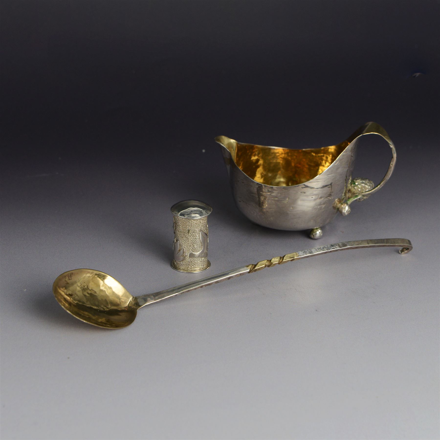 Modern silver cream jug, of circular form with gilt interior, gilt spiral decoration and planished finish throughout, the curved handle with berry detail to base, together with a silver cocktail spoon, with twist handle and a small pin box of cylindrical form, embossed with foliate decoration, all hallmarked Jonathan Braganza, London 2012 and 2013, cream jug H6cm