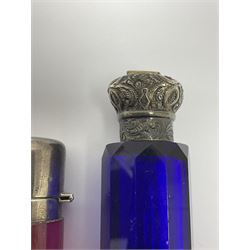 Late Victorian silver mounted ruby glass cylindrical scent bottle, with interior glass stopper, Birmingham 1900, makers mark worn, H8cm, together with a Victorian double ended cut blue glass perfume bottle mounted with white metal screw and flip caps decorated with foliate repousse detailing, H13.5cm