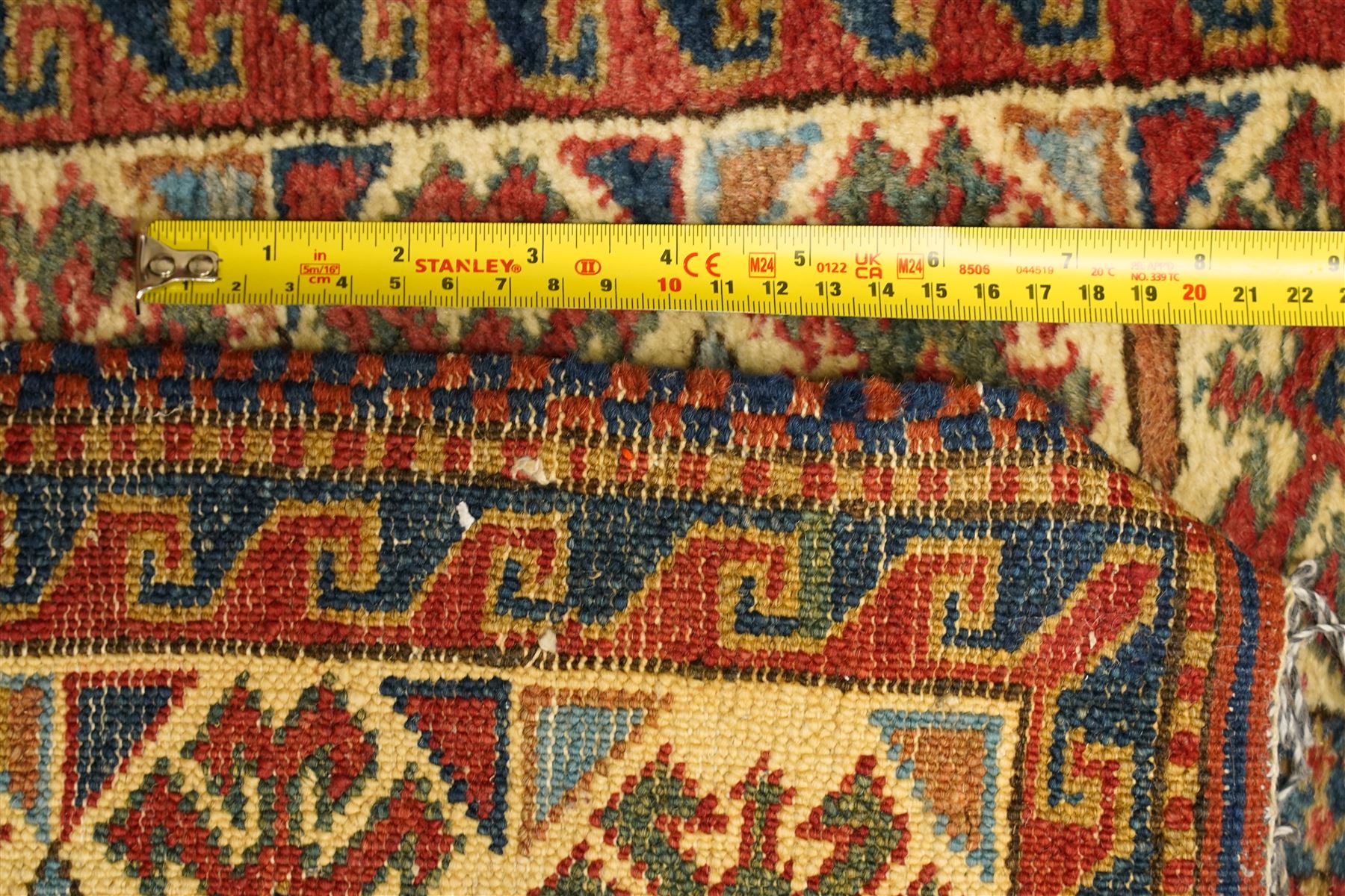 Caucasian hand-knotted runner, dark navy ground with three ivory geometric medallions surrounded by stylised flowerheads and angular motifs in madder red, green and ivory, enclosed by repeating geometric borders