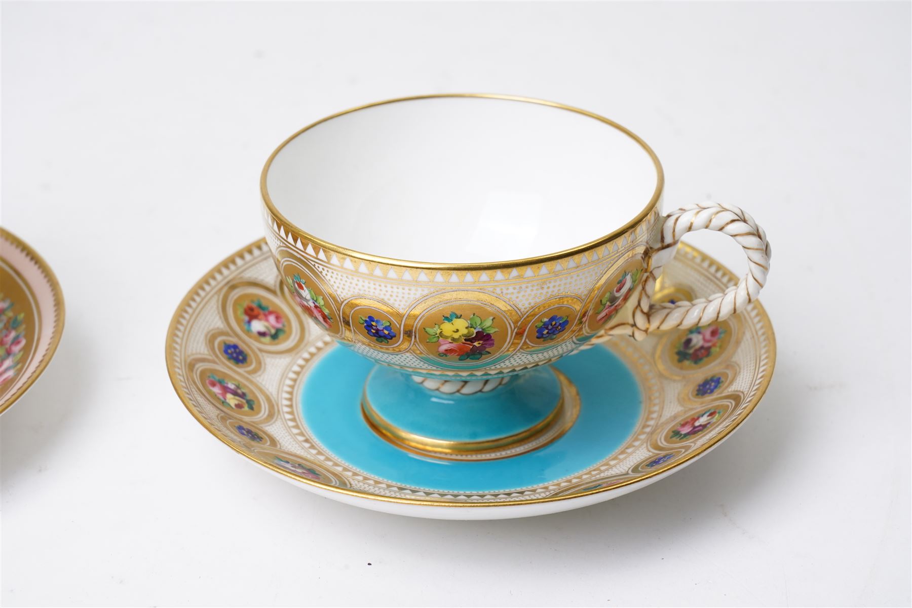 Brown-Westhead, Moore & Co cabinet cup and saucer, with rope twist moulded handle, hand-painted with floral reserves against a white and sky blue ground, heightened profusely with gilt, together with a pink hand-painted example, and a 19th century spill vase and twin-handled covered sucrier (4)