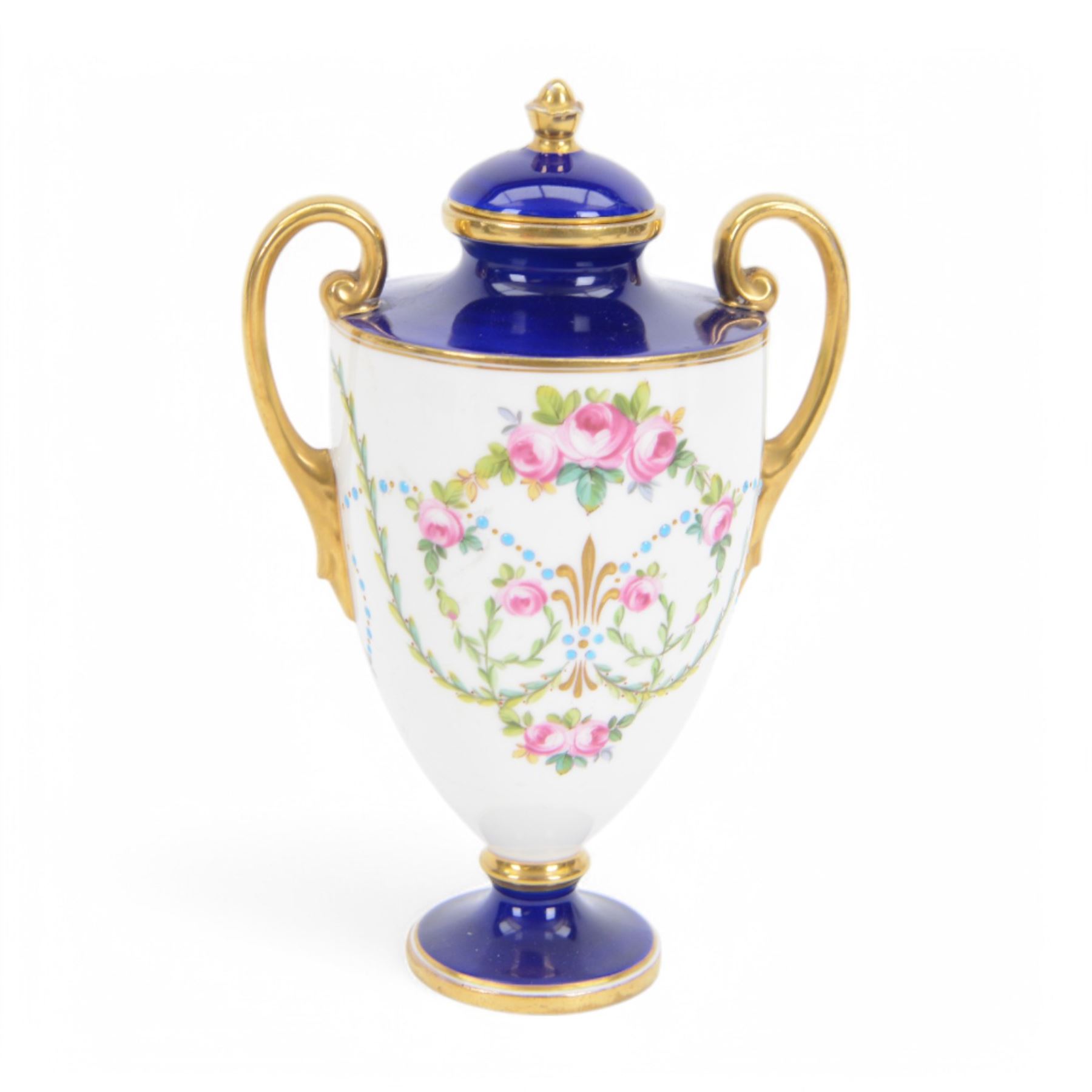 Early 20th century Minton porcelain twin handled pedestal cup, decorated with two reserve painted with birds against a blue ground, upon a square plinth painted with pink roses, the whole heighted with gilt, with puce printed mark beneath, H11.5cm, together with an early 20th century Minton twin handled vase, of ovoid form decorated with two painted portrait medallions, surrounded by gilt foliate scrolls, upon a blue ground, the neck painted with a band of pink roses, with gilt printed mark beneath, H11.5cm, and an early 20th century Minton twin handled pedestal vase and cover, painted with pink rose and vine swags upon a white ground, with puce printed mark beneath, H18.5cm, (3) 