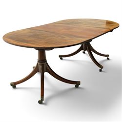 George III mahogany twin pedestal extending dining table, the twin D-ends with additional leaf, raised on twin turned pedestals terminating to four splayed supports with brass cups and castors