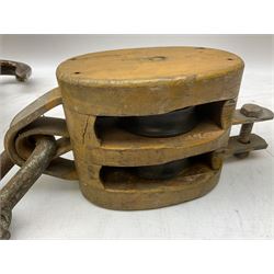Three ship pulleys comprising wooden block double with swivel eye marked 'wooden block 240mm double rope: 22mm',  wooden block double with upset shackle and wooden block with stiff swivel hook, largest example L50cm