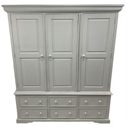 White painted triple wardrobe, projecting moulded cornice over three panelled doors, the interior fitted with hanging rails, four drawers and hinged cupboard to base, on bracket feet