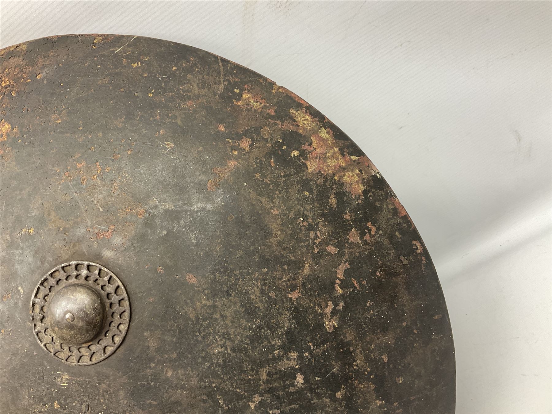 Indian black lacquered hide shield/dhal, of circular convex form fitted at its centre with four pierced iron bosses, each of hemispherical form with wide brims, the bosses corresponding on the inside with four iron rings for enarmes D53.5cm