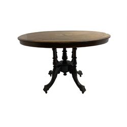 Late 19th century walnut loo table, oval top inlaid with foliate decoration and stringing, five turned columns united by circular base, raised on four acanthus leaf and scroll carved cabriole supports with brass and ceramic castors