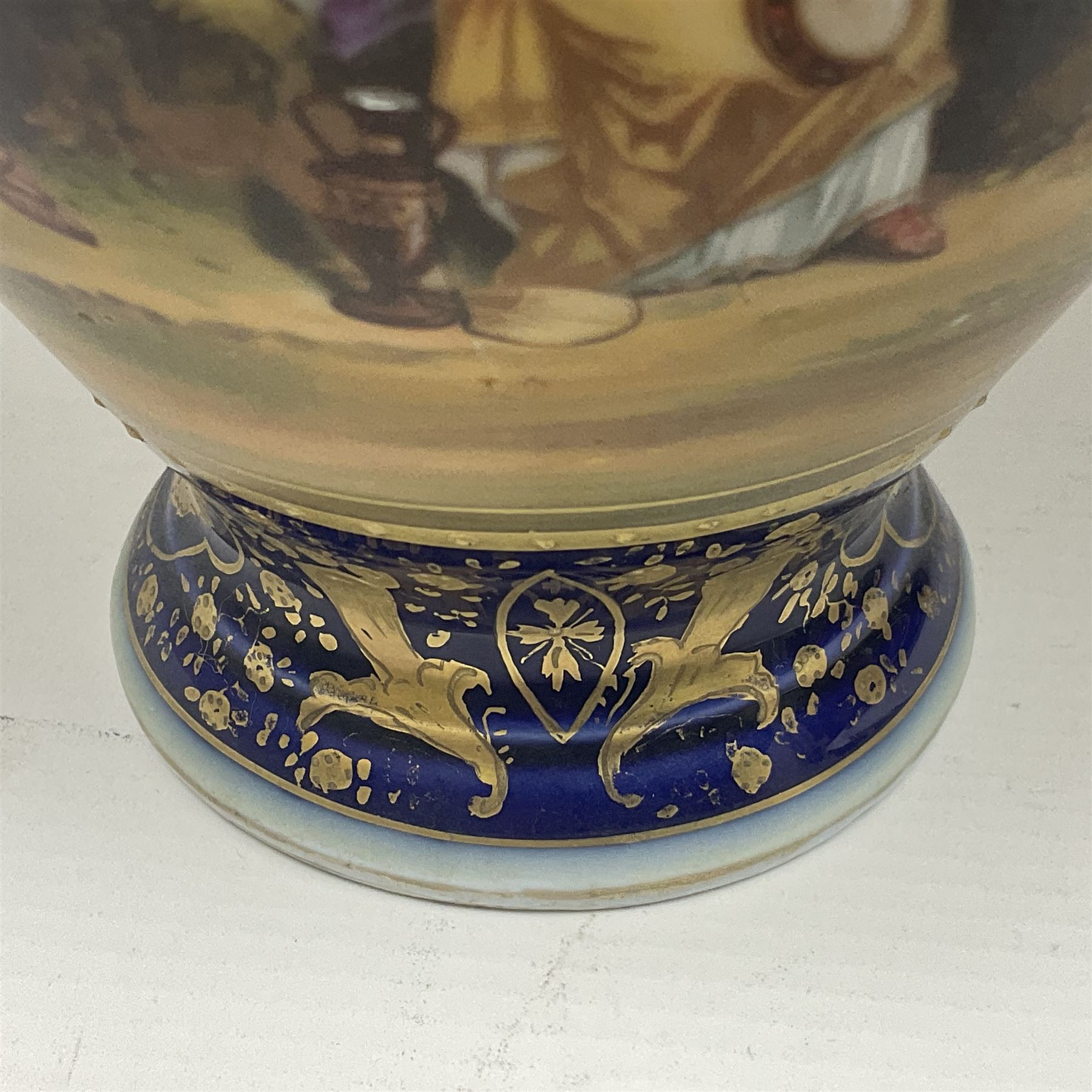 19th century Vienna style porcelain 'Musik' garniture, the central vase of baluster form with domed cover flanked by two smaller vases with twin curved gilt handles to short neck, each decorated with classical figural vignettes between blue borders heightened with gilt, H33.5cm