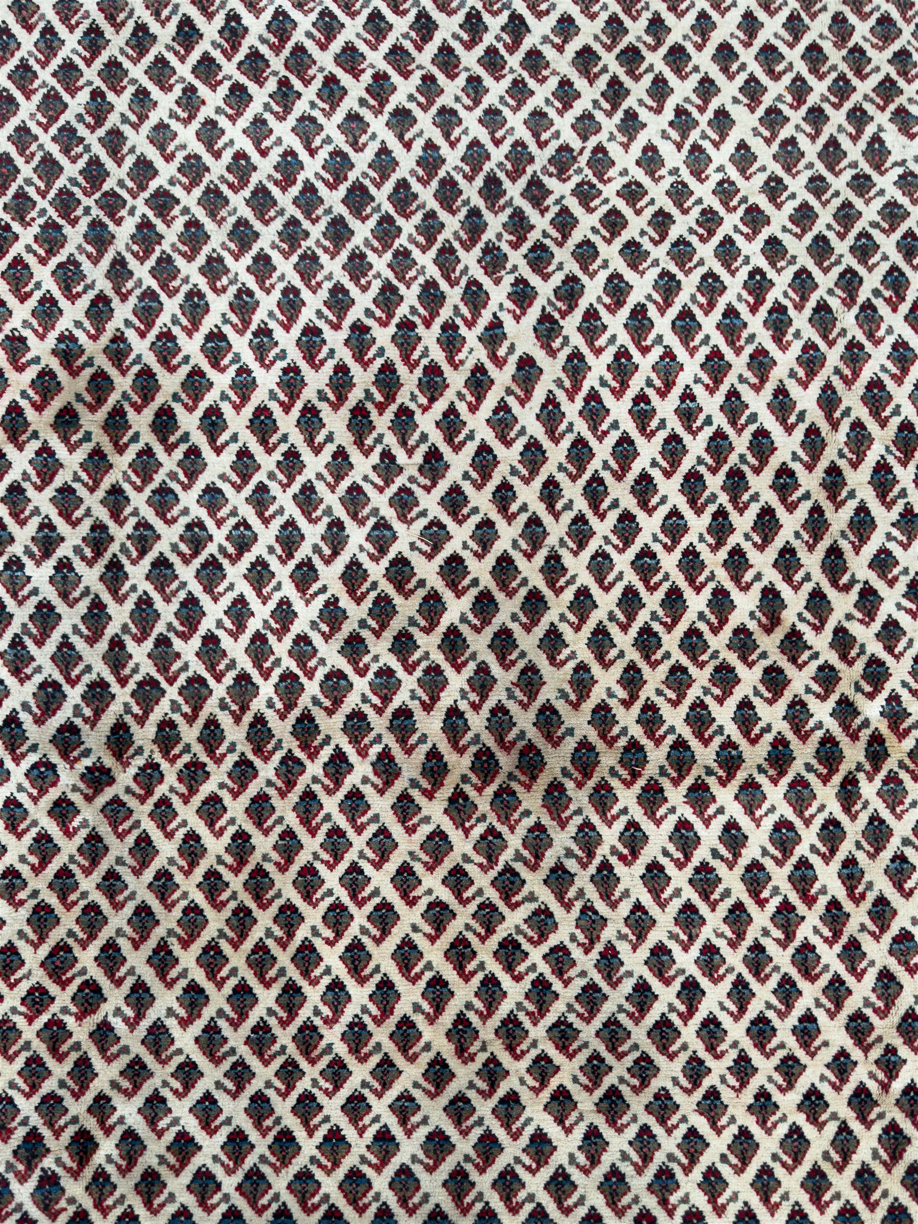 Northwestern Persian Bottehmir hand-knotted rug, ivory field with an all-over design of boteh motifs arranged in diagonal rows within multiple borders and a primary madder red field with stylized vine and flowerhead motifs, 320cm x 214cm 