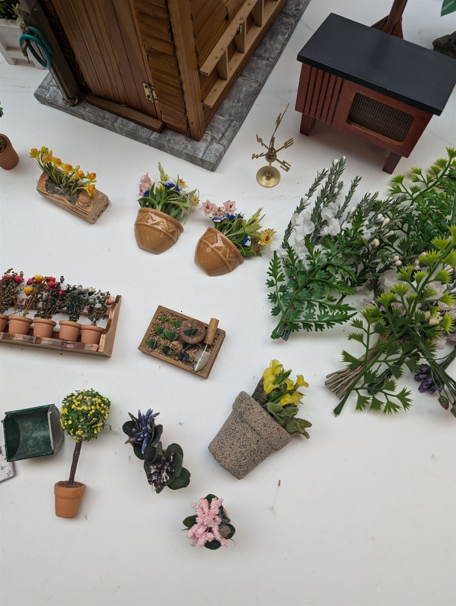 1:12 scale dolls house allotment and garden accessories, including wooden shed on a stone effect base, two vegetable patches, terracotta plant pots with flowers and foliage, stone effect plant pots, other planters, loose sunflowers, scarecrow, rabbit hutch, garden tools, fencing panels, etc 