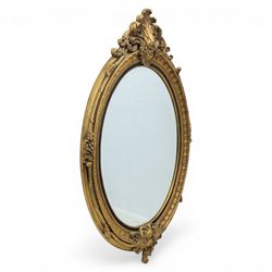 Rococo Revival style gilt composition oval wall mirror, moulded oval frame with fluted and...