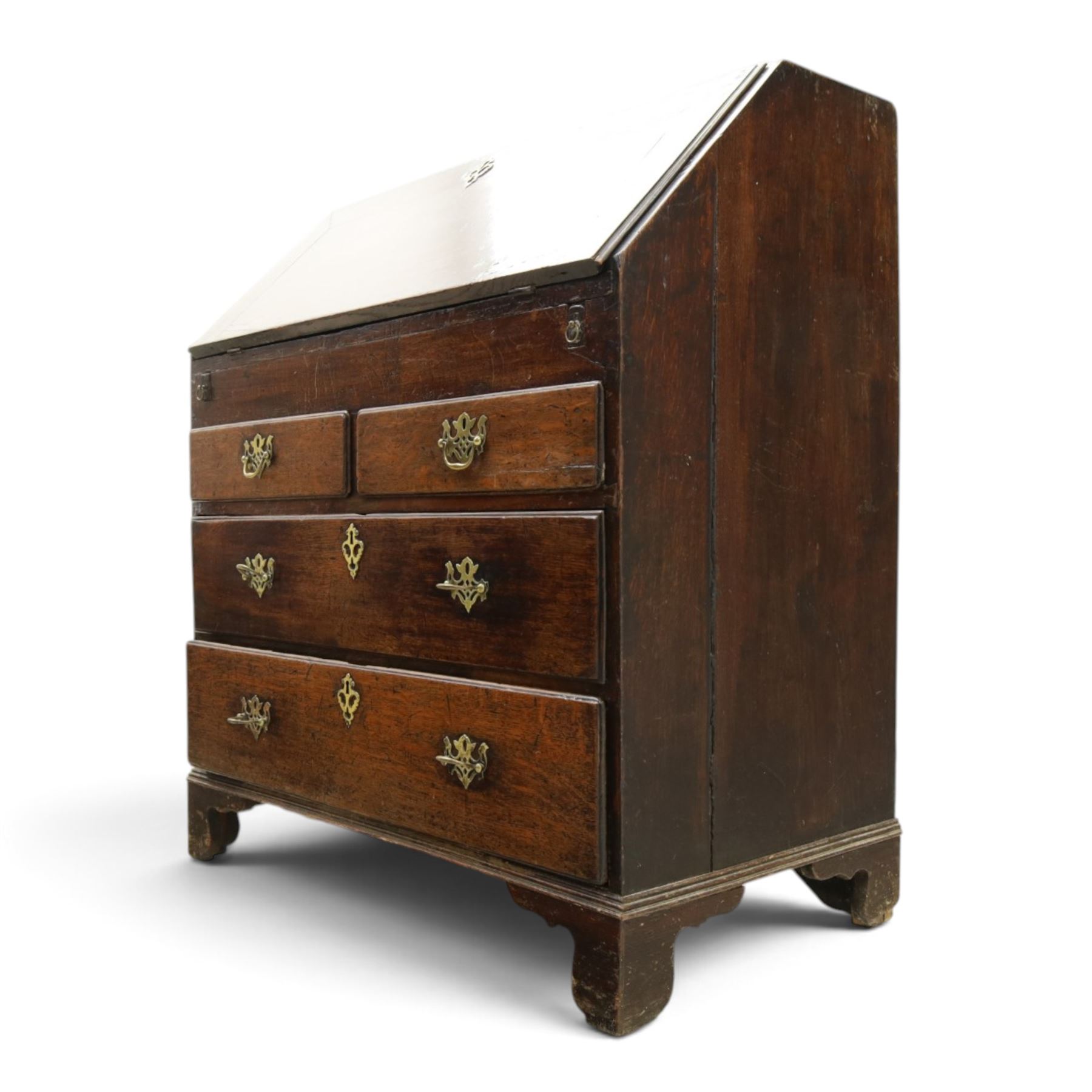 Georgian oak bureau, fall front with pierced brass escutcheon and handles, revealing a fitted interior, above two short over two long drawers, raised on bracket feet