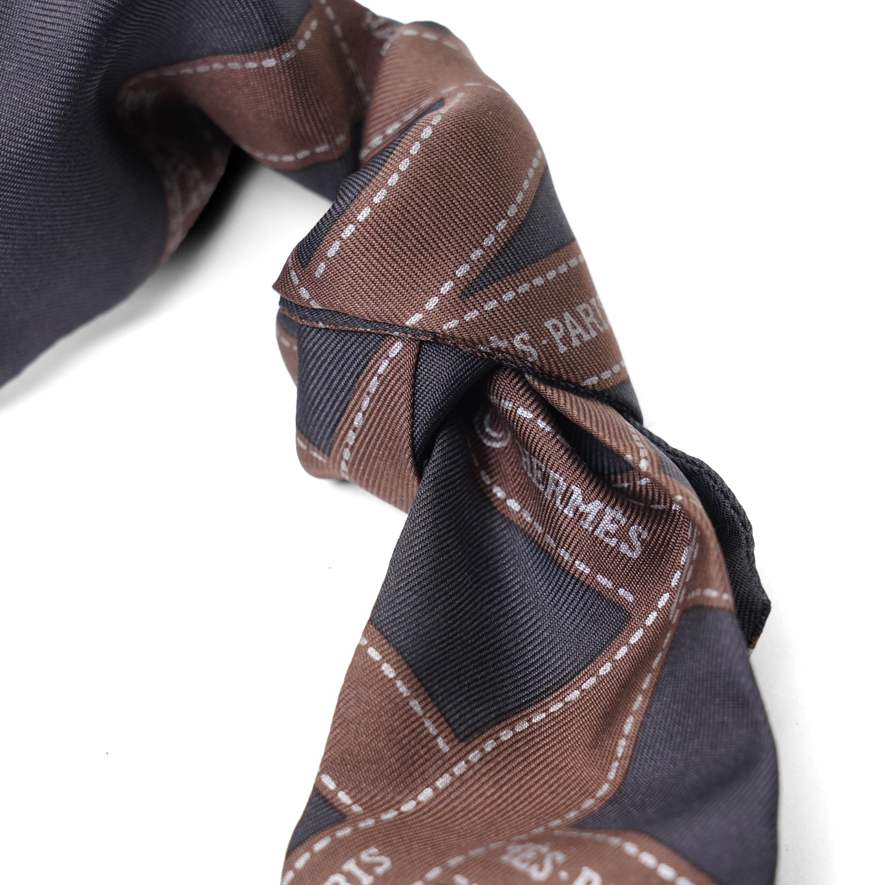 Hermès - two ‘Bolduc’ silk Twilly scarves, in orange/black and navy/brown colourways, together with three palladium-tone Médor pyramid Twilly scarf rings, with original dust bag and cylindrical box